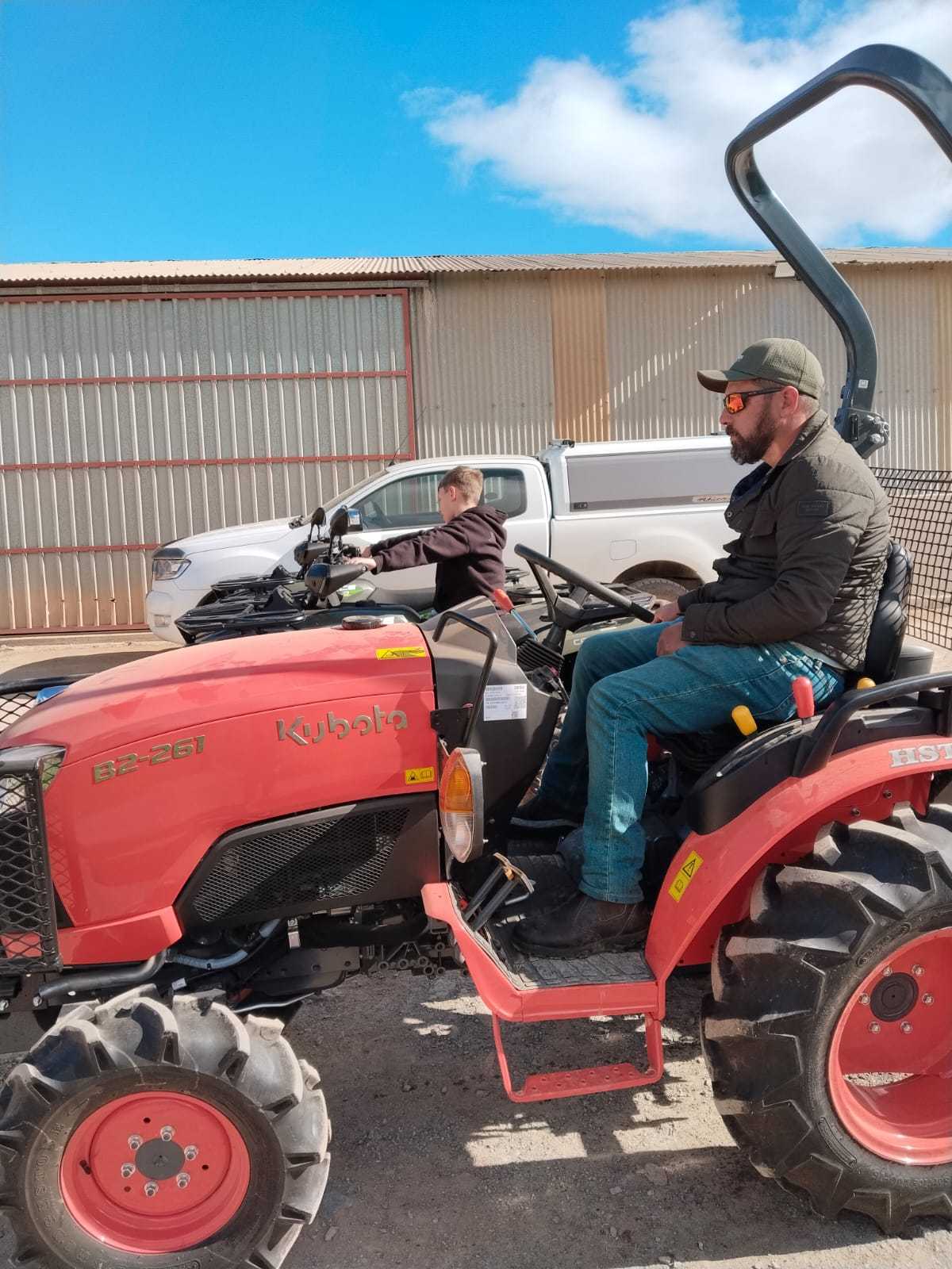 Japie-Douw on a red Kubota tractor outside the equipment shed, ready for the day.